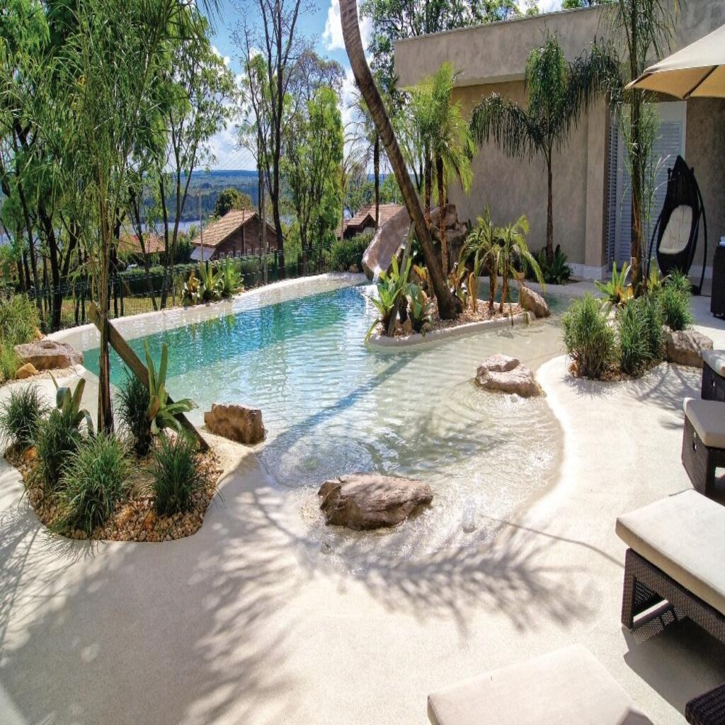 Piscina estilo praia integrada ao paisagismo com revestimento monolítico na cor Nassau