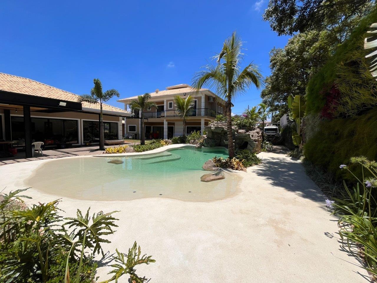 Piscina estilo praia com entrada gradual, formas orgânicas e revestimento Linha Beaches na cor Nassau